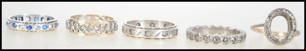 A group of four eternity rings along with one other all of which are silver and 9ct gold
