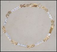 A hallmarked 9ct gold bracelet chain having gold a white stone lozenges with x link spacers and a