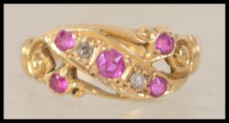 An 18ct gold vintage ladies gold and ruby diamond ring having a swirl mount interspersed with ruby