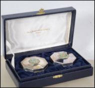 A pair of silver hallmarked pill boxes with enamel set tops and complete in the original