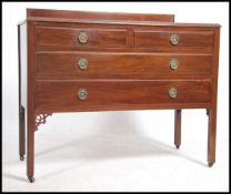 An Edwardian mahogany chest of drawers being raised on square tapered legs with short over deep