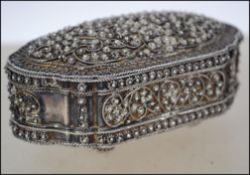 An Indian silver hinged lidded filigree trinket pot with cover bearing scroll work filigree floral