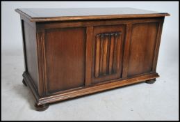 A 1950's Jacobean revival oak blanket box chest raised on bun feet with linen fold carved
