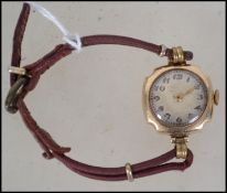 A 9ct gold 375 marked ladies dress watch being set to a leather strap. Decorative dial with