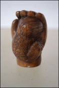 A Japanese carved wooden netsuke in the form of a fist signed to the edge
