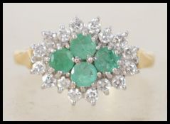 An 18ct gold, diamond and emerald ladies cluster ring. 4 central round cut emeralds surrounded by