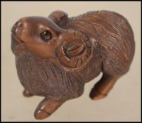 A Japanese carved netsuke in the form of a goat si