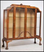 A 1930's Art Deco walnut china display cabinet of shaped form raised on ball and claw feet with