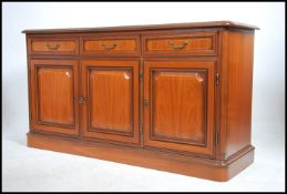 A contemporary mahogany sideboard having a series of drawers and cupboards with drop handles
