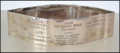 A silver ( tests as silver )  band with inscriptions to the front dating from 1958 - 1962 listing