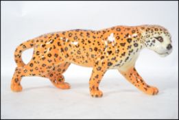 A large ceramic figurine by Beswick of a Leopard in a prowling position being stamped to the