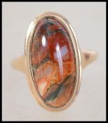 A 9ct gold and agate set ladies dress ring. The central elongated cabochon agate stone set to a