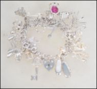 A silver charm bracelet containing many charms to include crown, slippers, animals, boat, horse,