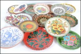 A large collection of mainly German studio pottery plates, most decorated with vibrant colours.