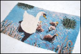 A retro 1970's woollen dyed floor rug of rectangular shape with images of swans and reeds etc