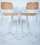 A pair of contemporary mid century style Industrial metal and bentwood bar stools being raised on