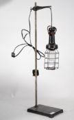 A vintage 20th century inspection lamp complete with wire cage raised on a cast metal base having