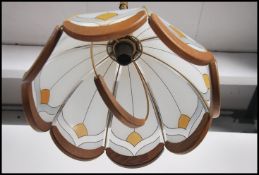 A pair of retro 1970's ceiling lights having frosted and colored glass half moon shades having oak