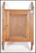 A 1920's hanging oak wall cabinet having shaped wa