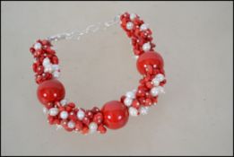 A silver cultured pearl and apple coral bracelet.