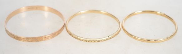 A group of three vintage rolled gold bangles two b