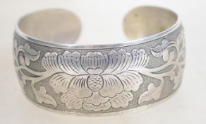 A heavy silver bangle bracelet having engraved fol