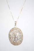 A large silver filigree oval pendant on a box link