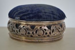 A large silver plated pin cushion with a pierced f