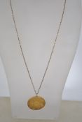 A sterling gilt silver coin pendant necklace on a