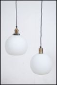 A near pair of milk glass and brass retro ceiling lights having orb sphere shaped glass shades.