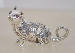 A cast silver figure of a cat with ruby eyes