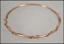 A 9ct gold slave bangle with applied vine and flow