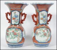 A pair of 19th century Chinese famille rose twin handled vases. Each with geometric red ochre panels