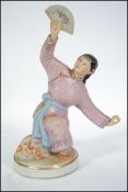 A 19th century Chinese figurine of a young girl kneeing with raised arm having fan to the hand.