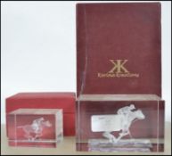 A pair of boxed glass paper weights each depicting a rider on horse playing polo by Karina