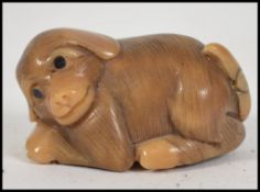 A Japanese hard wood netsuke carved as a seated do