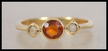 An 18ct gold ring set with an orange stone in a ru