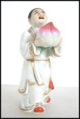 A believed 19th century Chinese figurine of a young boy holding a large peach. The boy in flowing