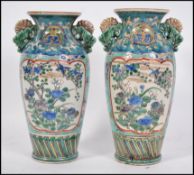 A pair of 19th / 20th century Chinese famille rose hand painted vases on blue ground with foliate