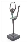 A decorative vintage cold painted cast metal sculpture of a young ballet dancer raised on a single