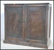 An Edwardian country oak estate cupboard being rai