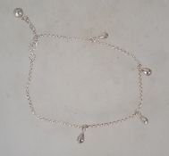 A sterling silver ankle bracelet having pendant drops and a small silver bell with a bolt ring