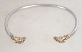 A hallmarked silver bangle bracelet, having detailed gilt rams' heads . Measures 7 cm wide, weighs