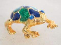 A signed gold tone enamel figural brooch in the form of a frog with roller clip clasp. Measures 3.