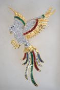 A large gold tone rhinestone set figural brooch in the form of a bird in flight with roller clip