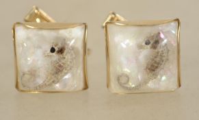 A vintage pair of 1970s cufflinks in gold tone metal with seahorses and iridescent glitter set in