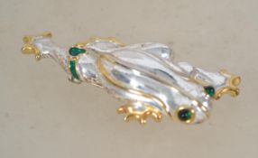 A vintage 1980s frog brooch being silver plated with green cabochon eyes with green enamel and a