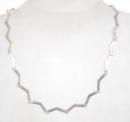 A sterling silver 925 rigid wave link necklace chain with claw clasp, having clear stone spacers.