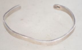 A hallmarked silver 925 bangle bracelet of wave form. Weighs 14.1 grams and measures 6 cm wide.