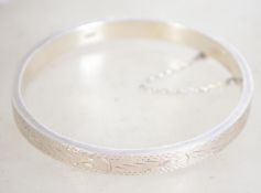 A sterling silver 925 bangle bracelet with safety chain, having full engraved foliate design.